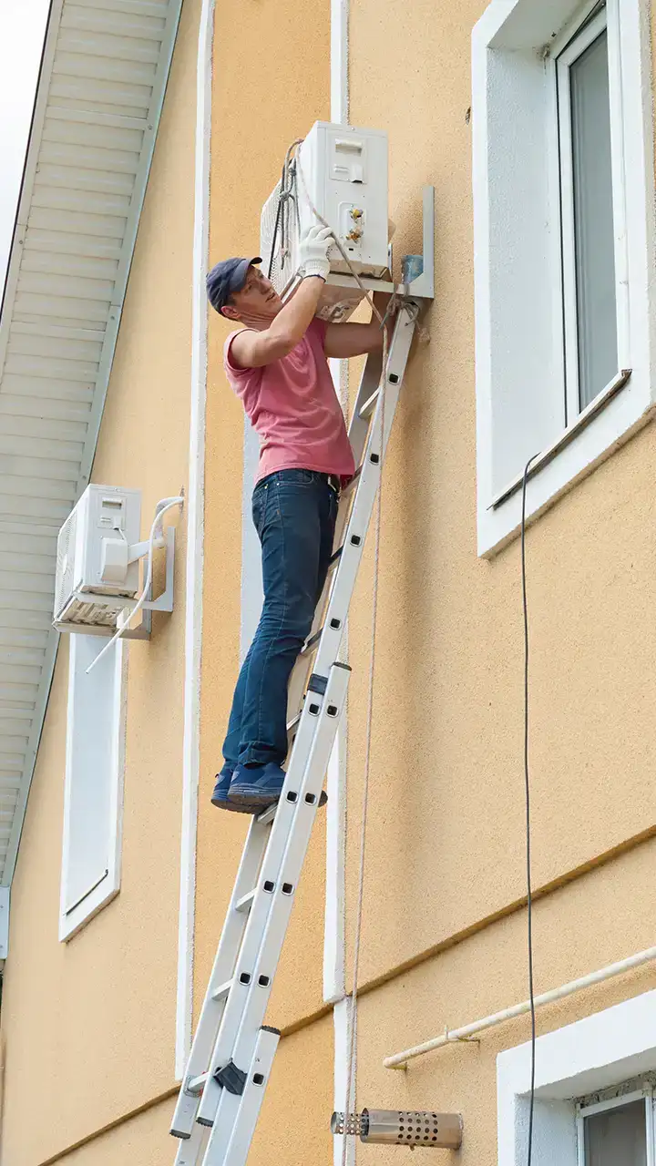 HVAC installer on ladder installing outdoor mini split unit | HVAC Installation Near Me | Fairhope HVAC Repair